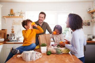Family unpacking grocery bags purchased with supermarket vouchers.